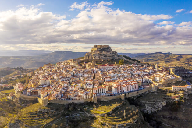 Luftaufnahme der mittelalterlichen Stadt Morella in Spanien mit Burg auf dem Hügel und Stadtmauer in hügeliger Landschaft