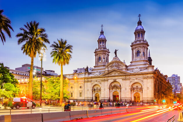 Barocke Kathedrale von Santiago de Chile mit beleuchteter Fassade und Palmen bei Sonnenuntergang. | Gebeco