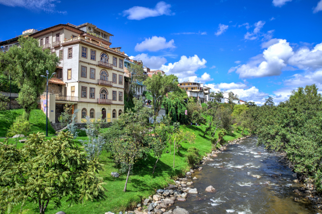 Ufer des Río Tomebamba in Cuenca Ecuador mit historischen Gebäuden und grüner Landschaft