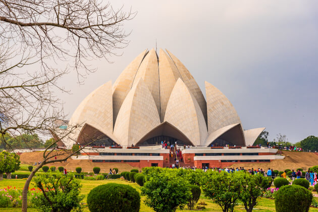 Außenansicht des Lotus-Tempels in Delhi bei blauem Himmel, spiegelnd im umliegenden Wasserbecken. | Gebeco