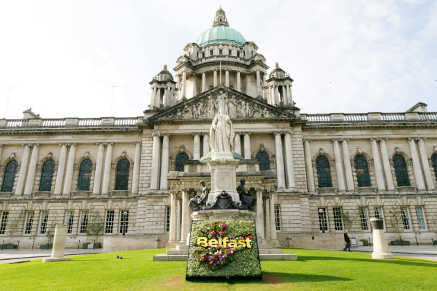 Historisches Rathaus von Belfast mit Blumeninstallation im Vordergrund bei sonnigem Wetter. | Gebeco