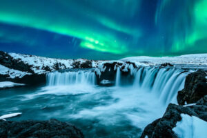 Grüne Polarlichter tanzen über dem Goðafoss-Wasserfall in winterlicher Schneelandschaft. | Gebeco