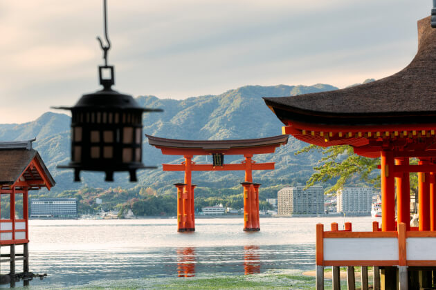 Torii-Tor des Itsukushima-Schreins auf der Insel Miyajima in Japan mit Blick auf das Meer und die Berge. | Gebeco