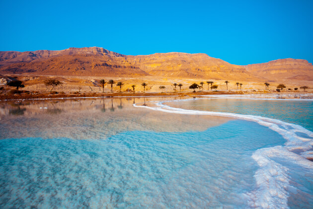 Salzküste am Toten Meer in Jordanien mit kristallweißen Salzablagerungen und türkisfarbenem Wasser unter blauem Himmel. | Gebeco