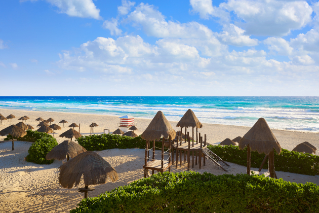 Playa Delfines in Cancún Mexiko mit Palapa-Sonnenschirmen, Spielplatz und Blick auf das karibische Meer
