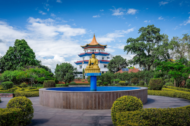 Buddhistischer Tempel in Lumbini Nepal mit goldener Statue im Garten. | Gebeco