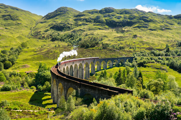 Dampflok auf dem Glenfinnan-Viadukt in den schottischen Highlands bei sonnigem Wetter. | Gebeco