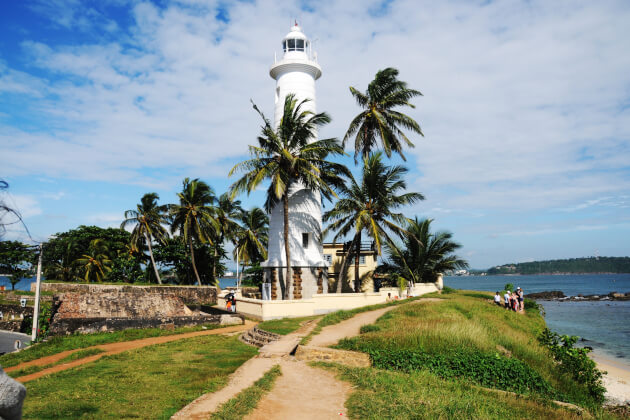 Galle Fort in Sri Lanka mit Blick auf den weißen Leuchtturm, koloniale Gebäude und das Meer unter bewölktem Himmel. | Gebeco