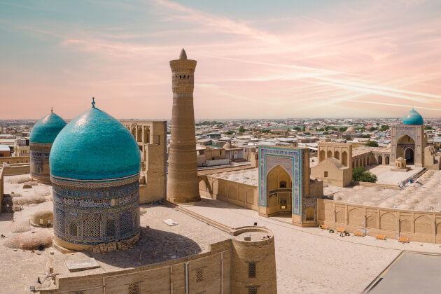 Panorama mit den türkisfarbenen Kuppeln des Chor Minor Ensembles und Minarett bei Sonnenuntergang in Buchara. | Gebeco