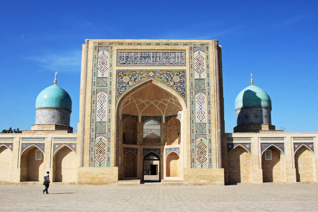 Frontansicht der Kukeldasch-Medrese mit zwei türkisfarbenen Kuppeln und reich verziertem Eingangsportal in Taschkent. | Gebeco