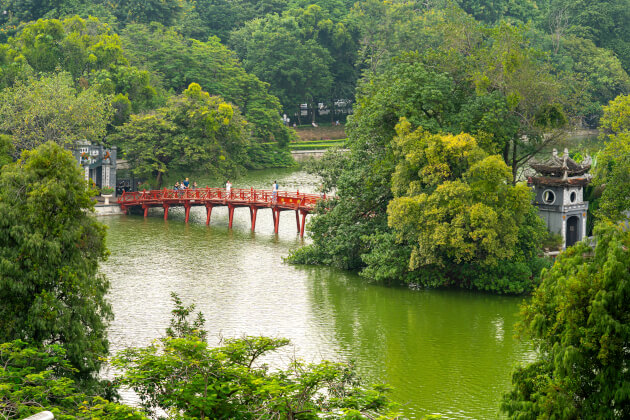 Rote Huc-Brücke über den Hoan-Kiem-See in Hanoi, umgeben von üppigem Grün. | Gebeco