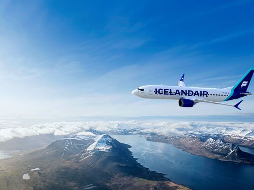 Icelandair Flugzeug über der isländischen Landschaft mit schneebedeckten Bergen, Fjorden und Seen, Luftaufnahme Island mit blauem Himmel und weißen Wolken.