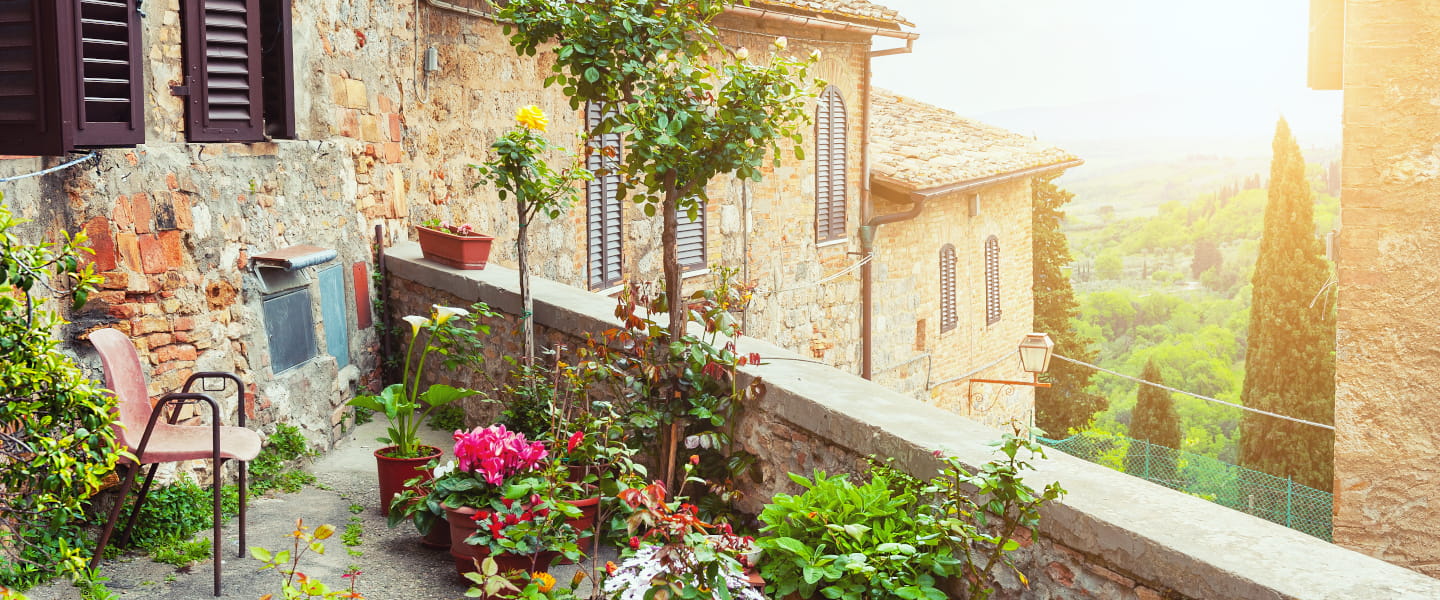 Toskanische Terrasse | Blumen, Steinmauer und Panoramaausblick Zu unseren Italien-Reisen