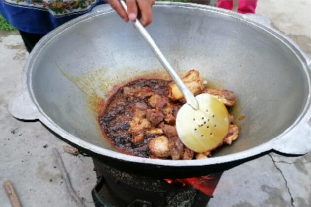 Fleischstücke werden im großen Kazan über offenem Feuer angebraten – erster Schritt der Plov-Zubereitung.