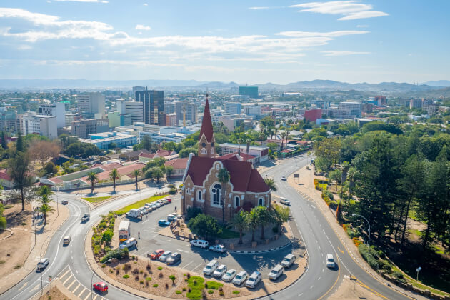 Christuskirche in Windhoek (Luftaufnahme) im Kreisverkehr mit Innenstadt und Hügeln im Hintergrund